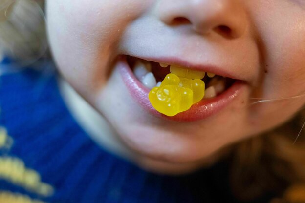 Ein Kind beißt auf ein Gummibärchen