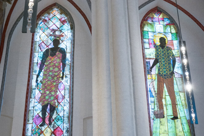 Kunstwerke aus Stoff an einem Kirchenfenster.