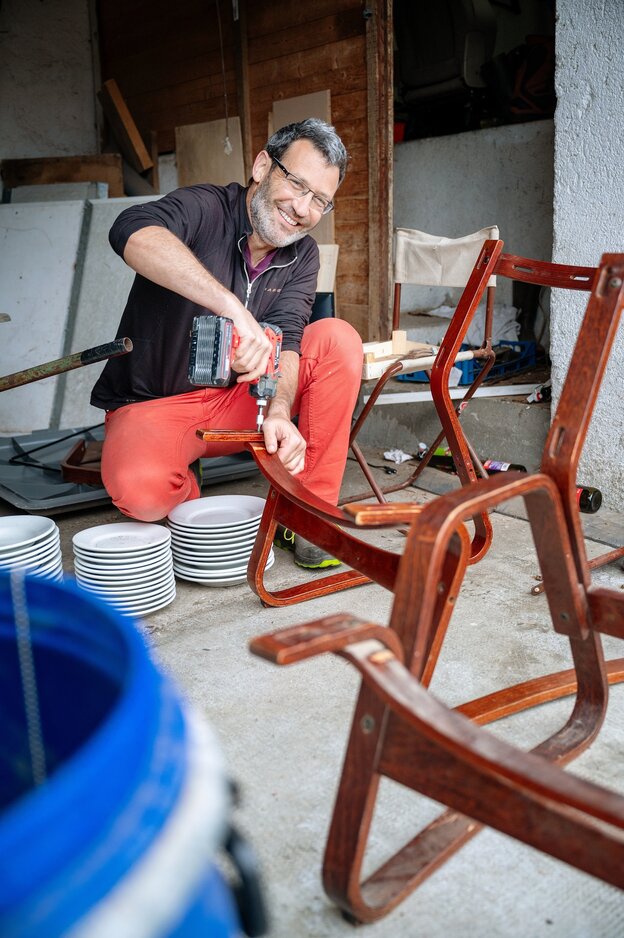 Ein mann repariert Stühle, er hält eine Bohrmaschine in den Händen