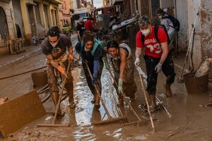 Menschen reinigen eine mit Schlamm überschwemmte Straße