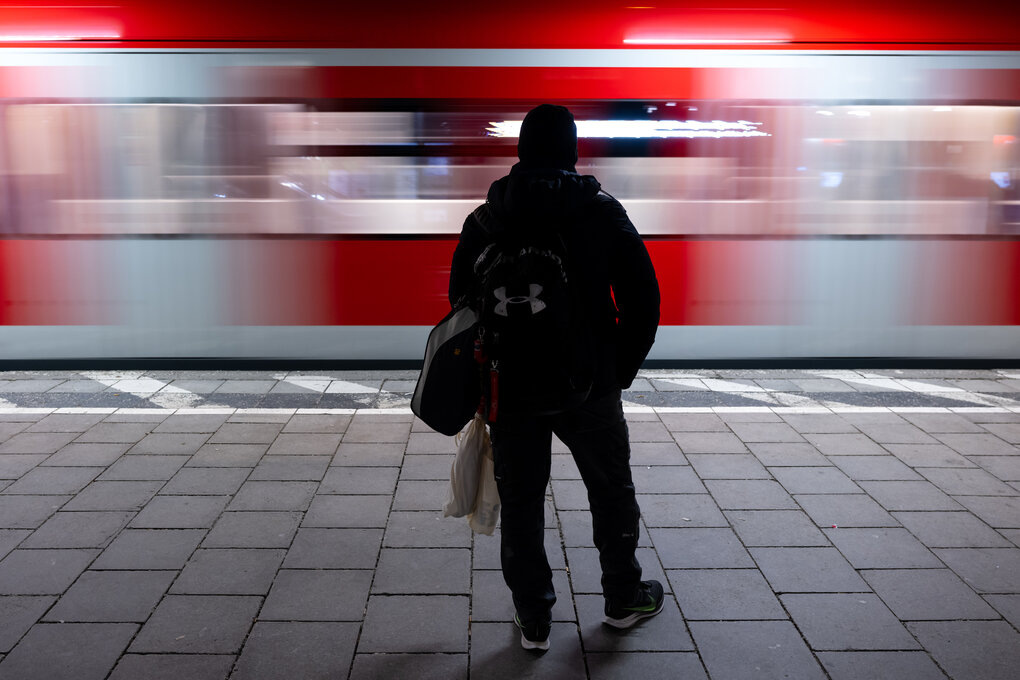 Ein Mann am Bahnsteig sieht auf fahrenden Zug