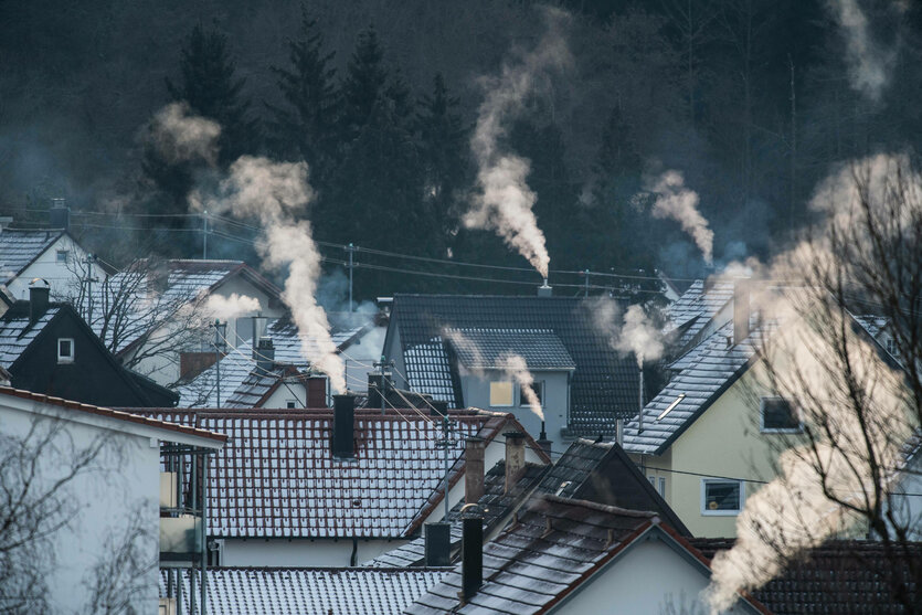 Weißer Dampf steigt bei eisigen Temperaturen aus Schornsteinen von Wohnhäusern auf