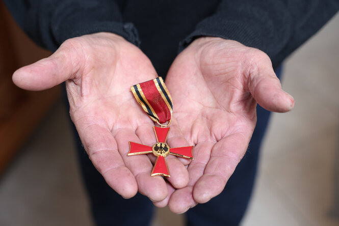 Verdienstkreuz in den Händen