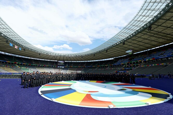 Polizeibeamte stellen sich im Olympiastadion hinter dem am Boden drappierten EM-Logo für ein Foto auf