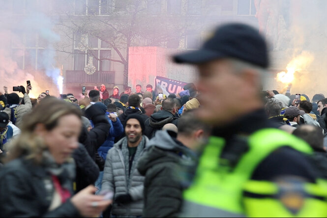 Israelische Maccabi Tel Aviv-Anhänger demonstrieren und zünden Leuchtraketen an, während ein Polizist in Amsterdam, Niederlande, am 7. November 2024 in diesem Screenshot aus einem Social-Media-Video patrouilliert