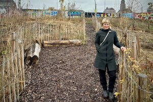 Eine Frau steht vor einer eingeäzunten kahlen Fläche