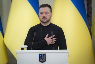 Selenskyj vor Ukraine-Flagge mit Hand auf der Brust