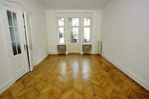 Ein großes Zimmer mit Parkettboden in einer Altbauwohnung mit Balkon und Flügeltüren