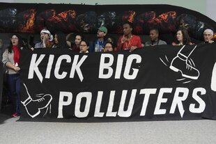 Demonstrierende mit Banner "Kick big polluters"