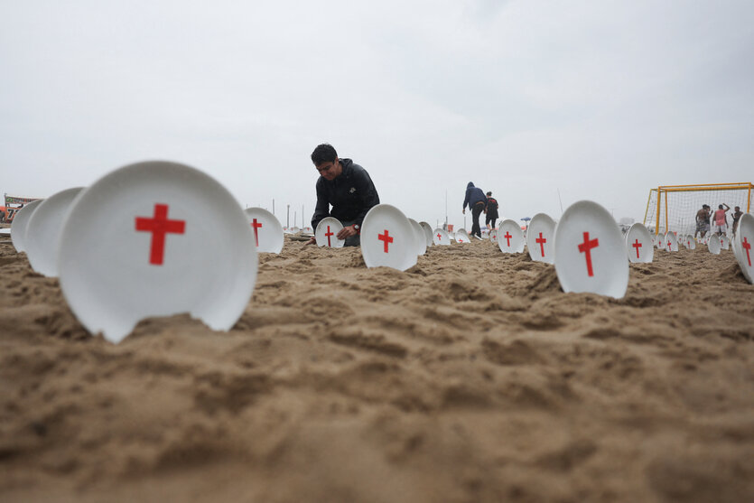 Ein Strand mit leeren weißen Tellern. Zwei Männer im Hintergrund