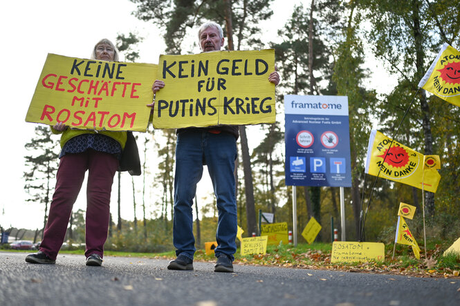 Menschen halten gelbe Plakate mit der Aufschrift „Keine Geschäfte mit Rosatom“ und „Kein Geld für Putins Krieg“