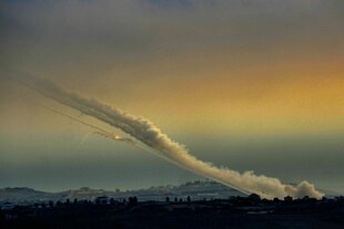 Spuren von aufsteigenden Raketen vor einem gelb-blauen Abendhimmel