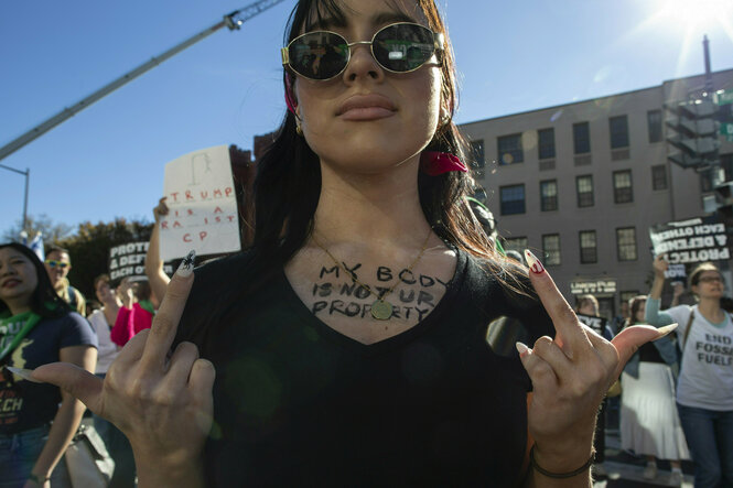 Eine Person zeigt bei einer Demonstration ihre Mittelfinger.