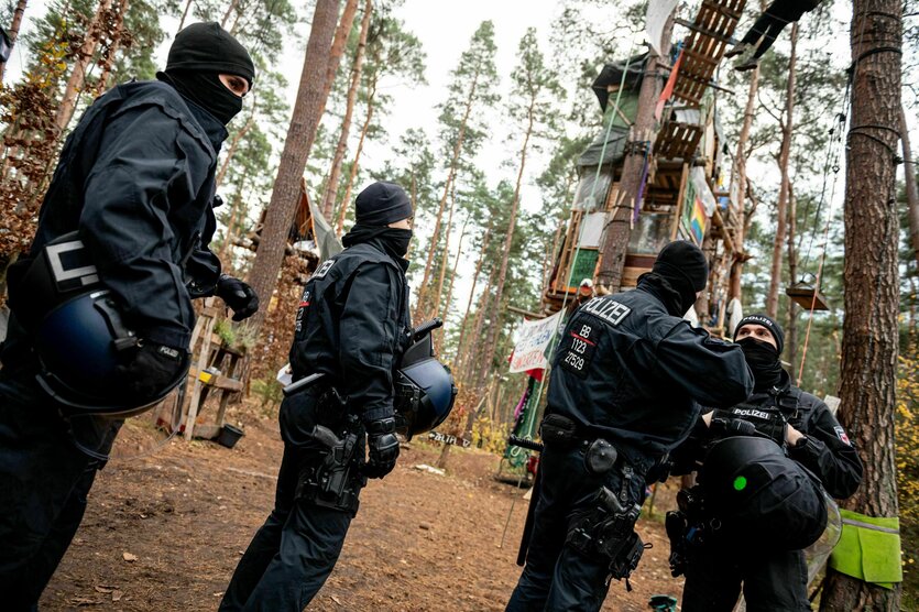 Polizist:innen vor einem Protestcamp in Bäumen.