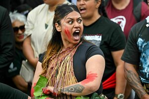 Eine indigene Māori protestiert in einer Menschenmenge mit aufgerissenen Mund und Augen