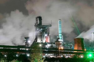 Die Lichter einer in Rauch gehüllten Fabrikanlage in der Nacht