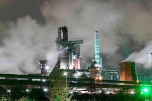 Die Lichter einer in Rauch gehüllten Fabrikanlage in der Nacht