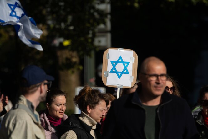 Menschen auf einer Demonstration für die Freilassung der israelischen Geiseln in Gaza, eine Person hält ein Pappschild mit einem blauen Davidstern