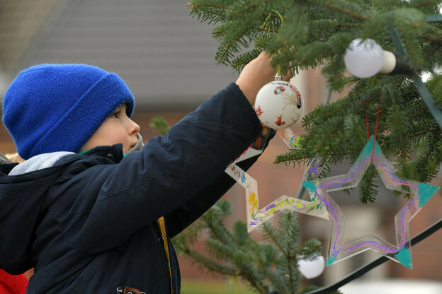 Ein Kind schmückt einen Christbaum