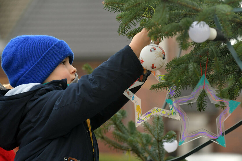 Ein Kind schmückt einen Christbaum