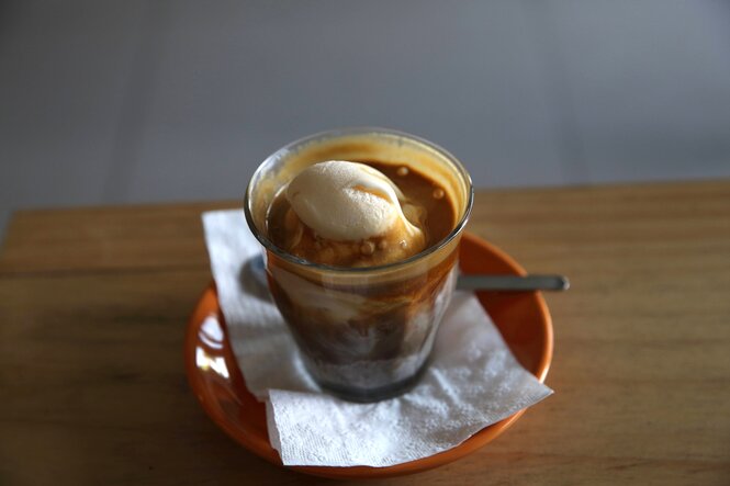 Ein Glas steht auf einem Tisch, darin ist eine Kugel Vanilleeis und Espressokaffee