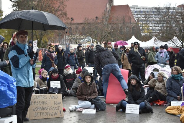 Demonstration, bei der Menschen auf dem Boden sitzen, zum Teil in Schlafsäcke gehüllt.