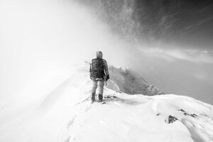 Wanderin von hinten zu sehen auf einem verschneiten Berg