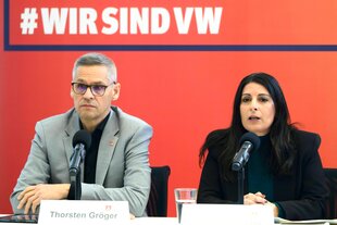 Thorsten Gröger, IG Metall-Verhandlungsführer, und Daniela Cavallo, Gesamtbetriebsratsvorsitzende Volkswagen, sprechen bei einer Pressekonferenz. Sie sitzen vor einer roten Wand auf der steht, #Wir sind VW