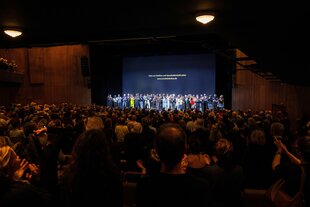 Eine Bühne mit vielen Künstlern, viele Zuschauer im Berliner Ensemble, die stehend applaudiren