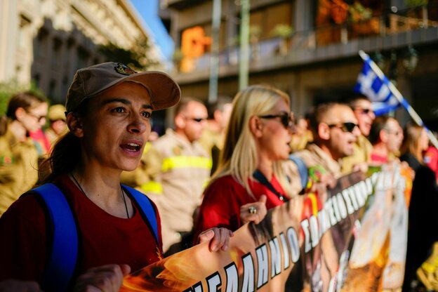 Weibliche Feuerwehrleute tragen ein Banner während einer Kundgebung