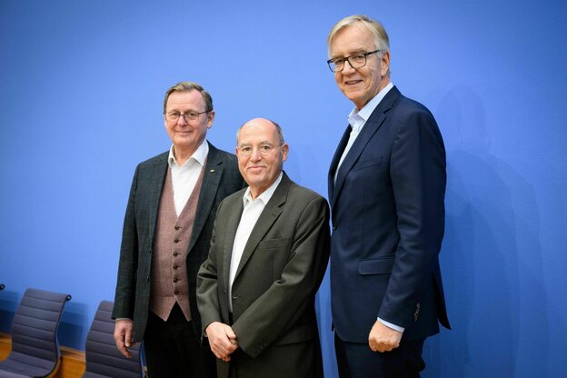 Drei Männer im Anzug aber ohne Krawatte stehen vor einer blauen Wand: Bodo Ramelos, Gregor Gysi und Dietmar Bartsch von der Linken