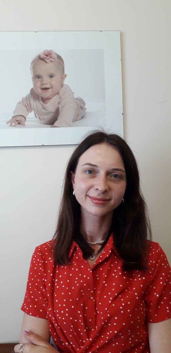 Eine junge Frau in roter Bluse vor einem Babyfoto