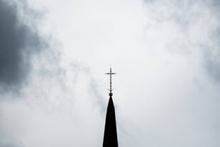 Ein Kirchturm mit einem Kreuz auf der Spitze