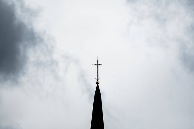 Ein Kirchturm mit einem Kreuz auf der Spitze