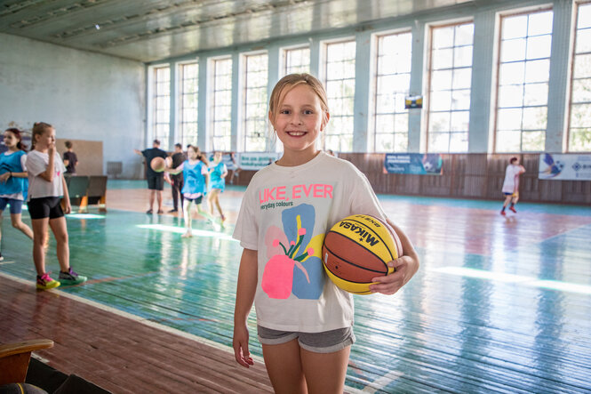 Ein Mädchen in einer Turnhalle mit einem Basketball