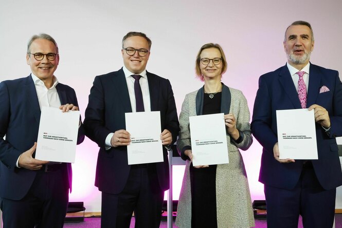 Zwei Männer und eine Frau lachen in die Kamera