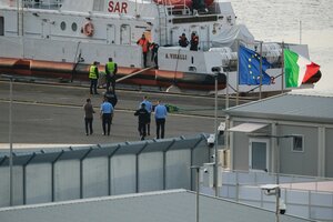 Ein Sicherheitsbeamter geht vor einem Schiff der italienischen Küstenwache, das sich auf die Abfahrt vom Hafen von Shengjin, Albanien, nach Italien vorbereitet