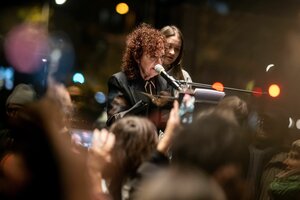 Eine Frau mit lockigen Haaren steht auf einem Podium