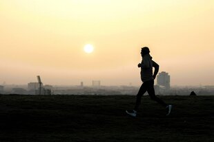 Ein Jogger zeichnet sich vor der aufgehenden Sonne ab in Berlin