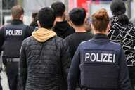 Polizisten der Bundespolizei führen auf dem Hauptbahnhof ankommende Flüchtlinge aus Syrien zum Bereich für die Registrierung.