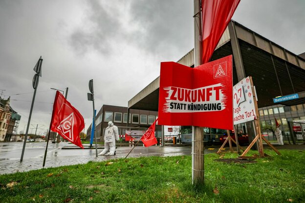 Vor der Einfahrt auf das Werksgelände von Thyssenkrupp Steel in Duisburg hängen Protest-Plakate und Fahnen der IG Metall