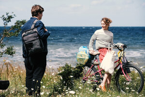 Eine Frau steht an ihrem Fahrrad und unterhält sich mit einem Mann, im Hintergrund das Meer.Szene aus Christian Petzolds Film 