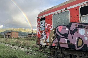 Ein Eisenbahnwaggon mit Graffiti und ein Regenbogen.