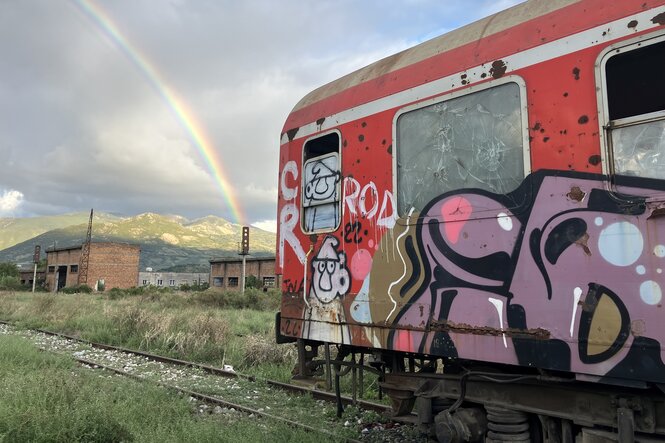 Ein Eisenbahnwaggon mit Graffiti und ein Regenbogen.