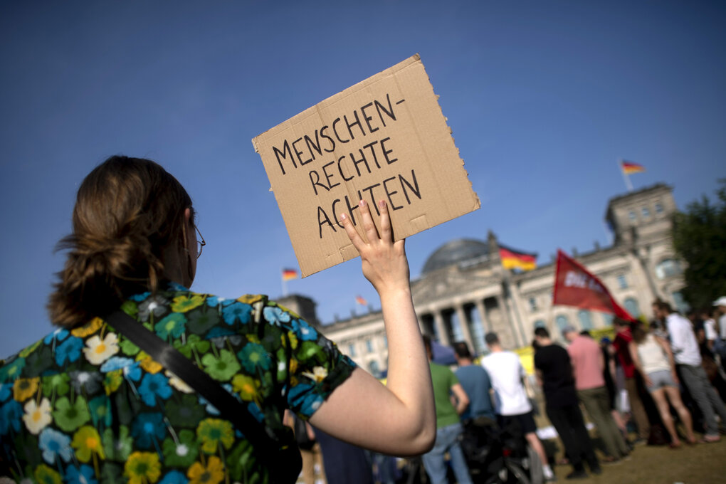 Eine Frau hält ein Protestschild hoch, auf dem steht:"Menschenrechte achten"