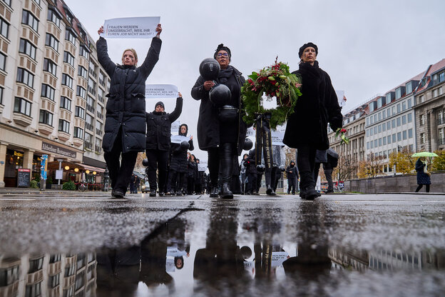 In schwarz gekleidete Frauen marschieren über eine regennasse Straße