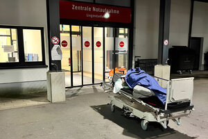 Ein fahrbares Krankenhausbett, darauf ein Mensch unter einer Decke