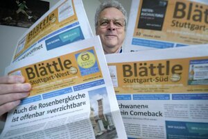 Ein Mann hält verschiedene Ausgaben einer Lokalzeitung hoch