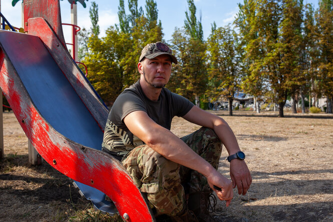 Ein Soldat sitzt auf einer Rutsche auf einem Spielplatz.