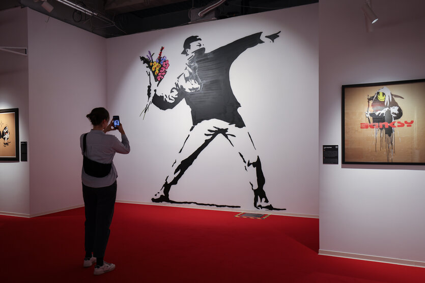 Eine Frau betrachtet das Wandbild "Flower Thrower" in der Ausstellung "House of Banksy - An Unauthorized Exhibition" in Hamburg.